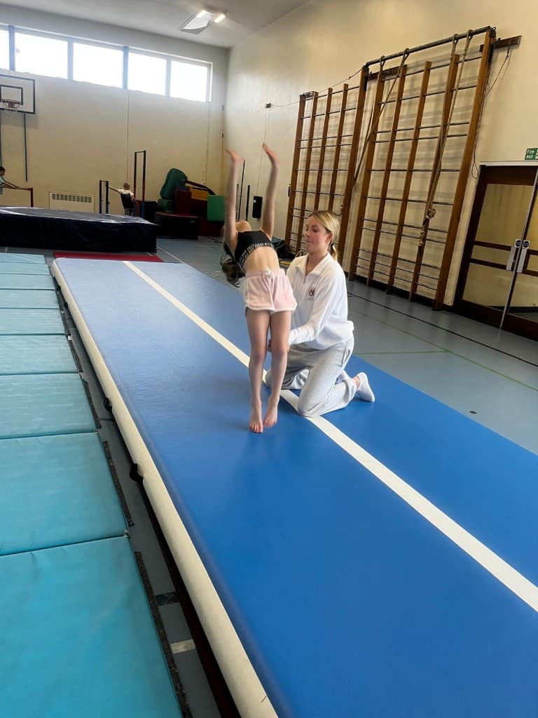 A coach spotting a gymnast on the air track at Mary Erskines School, MES sports centre